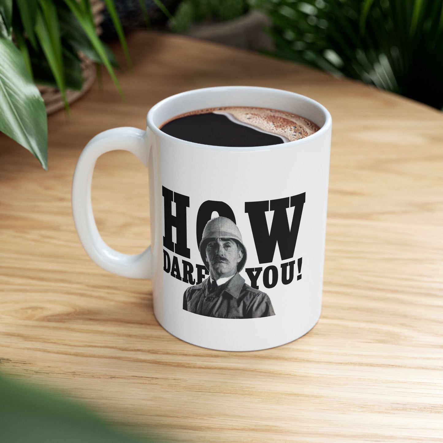 White ceramic mug featuring a stern British soldier and the phrase "How Dare You," placed on a table with a clean, minimalist background.