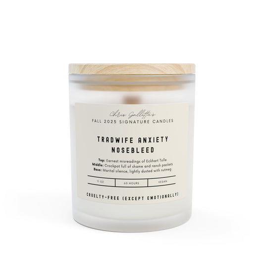 A frosted glass candle labeled “Tradwife Anxiety Nosebleed” with a maple wood lid, styled on a neutral-toned surface. The label features clean, modern typography with satirical branding.